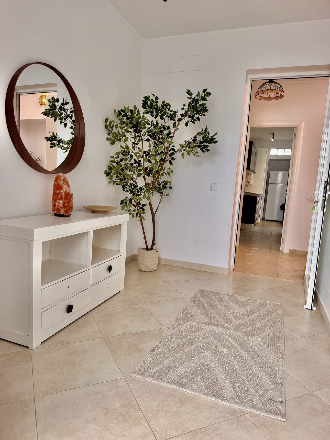 Welcoming entrance hallway with round mirror and tree